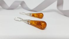 A beautifully crafted unique Baltic Amber pair of earrings. Featuring large teardrop shaped cognac Amber gemstones with a detailed sterling silver frame.Material: Authentic Baltic Amber and 925 sterling silverDimensions: 56 x 10 mm ( 2.20 x 0.39 in )Color: CognacFastening: Lever backFinish: PolishedThe Amber gemstones are a deep and classic cognac hue which shines brightly in natural light. The Amber teardrops are full of natural intricate flakes. The gorgeous open sterling silver work feature o Brown Long Drop Earrings For Gift, Elegant Amber Teardrop Earrings, Elegant Brown Teardrop Earrings For Gift, Amber Teardrop Earrings Gift, Amber Teardrop Earrings As A Gift, Amber Teardrop Drop Earrings For Gift, Elegant Brown Pierced Teardrop Earrings, Hypoallergenic Amber Teardrop Earrings, Orange Teardrop Earrings For Formal Occasions