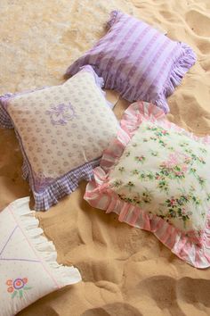 four decorative pillows laid out on the sand