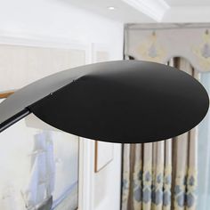 a black lamp hanging off the side of a wall in a room with paintings on the walls