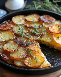 a pan filled with sliced up potatoes on top of a wooden table