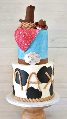 a three tiered cake decorated with cowboy hats and rope