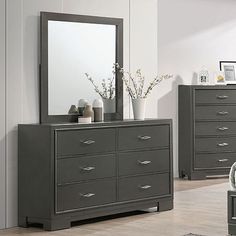 there is a dresser and mirror in the room with white walls, hardwood flooring and gray furniture