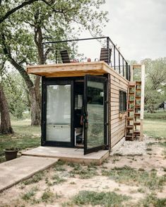 a small wooden cabin sitting in the middle of a field with stairs leading up to it