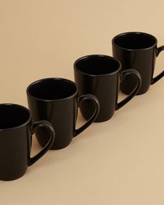 four black coffee mugs lined up in a row