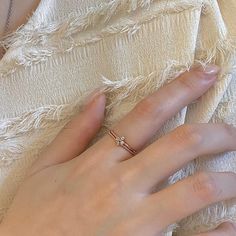 a woman's hand with a diamond ring on her finger, resting against a white blanket