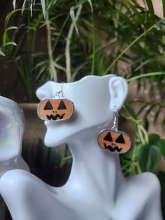 a pair of earrings with carved jack - o'- lantern faces on them sitting next to a potted plant