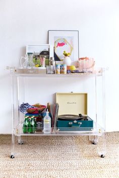 an acrylic shelf with various items on it in front of a white wall