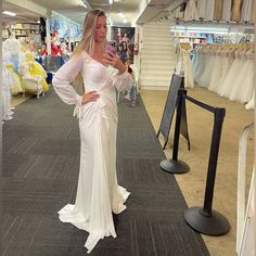 a woman in a white dress is looking at her cell phone while standing on the carpet