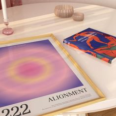 a book sitting on top of a white table next to a candle and some vases