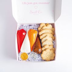 a box filled with assorted cookies and other treats on top of a white table