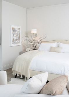 a bedroom with white furniture and pillows on the bed