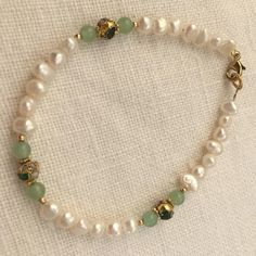 This lovely freshwater pearl bracelet has small navy cloisonné beads with pink flowers and green leaves, gold-plated flower beads and tiny green aventurine beads. It is understated elegance.  Measures: The bracelet 7 3/4" of wearable space (8" from end to end).  Of the beads are 5 mm wide. Material: -- 5 x 7 mm freshwater pearls -- 4 mm green aventurine beads -- Navy cloisonné beads with pink and green -- gold-plated seed beads and flower spacers -- gold-plated lobster claw (22 kt. gold over ste Diy Green Bracelet, Green Pearl Bracelet, Elegant Green Pearl Hand-strung Bracelet, Elegant Green Hand-strung Pearl Bracelet, Pastel Bracelet, Ruby Bangles, Beaded Memory Wire Bracelets, Green Beaded Bracelets, Indie Jewelry