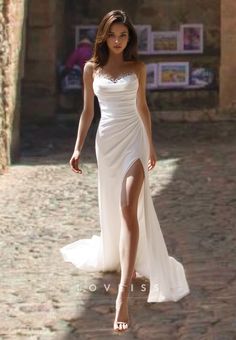 a woman is walking down the street in a white dress with high slits on her legs