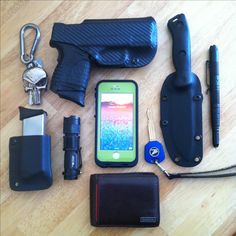 an assortment of personal items laid out on top of a wooden table next to a cell phone