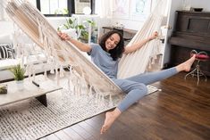 a woman laying in a hammock with her feet up on the floor and smiling