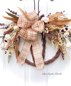 a wreath is hanging on the front door with an orange plaid bow and white flowers