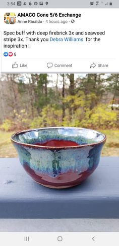 a bowl sitting on top of a wooden table next to a window with trees in the background