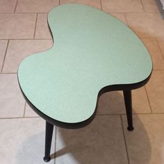 a green table sitting on top of a tiled floor