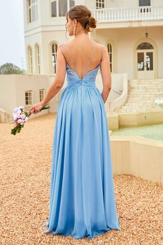 a woman standing in front of a building wearing a blue dress and holding a bouquet