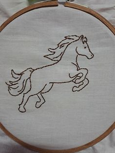 a white embroidered horse with brown trim on it's face and tail running through the air