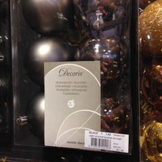 christmas ornaments are on display for sale in a store window with gold and silver decorations