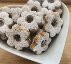 a white bowl filled with donuts covered in powdered sugar