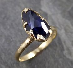 a gold ring with an oval shaped blue stone in the center, on a gray surface