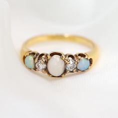 DETAILS   ------------------------------------------------  Material: 18 Carat Yellow Gold Stones: Opal & Diamond Stone Shape: Oval Cabochon Cuts  Carat Weight: 0.40 Colour: G Clarity: S! Size: EU 50.6 - UK K.5 - US 5½  ------------------------------------------------     This lovely Victorian ring features alternating opals and diamonds. The centre opal is 0.20 carat, while the two opals on the sides are 0.10 carat each. The two old cut diamonds are 0.10 carat each, and are G in colour and SI clarity. The gems are beautifully claw set in the 18 carat yellow gold setting. This ring would have been made entirely by hand around 1900. --------------------------------------------------------   Each item in our collection is meticulously chosen for its beauty, quality, and historical significan Opal Diamond Ring, Opal Birthstone, Victorian Ring, Art Deco Diamond Rings, Victorian Rings, Yellow Gold Setting, Art Deco Diamond, Elegant Ring, Oval Cabochon