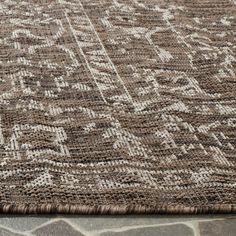 a brown and white rug on top of a stone floor