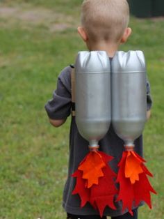 a young boy holding two silver cups with red leaves on them