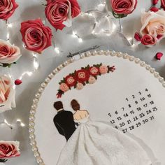 a wedding cake decorated with roses and a couple holding each other's hand on top of a table