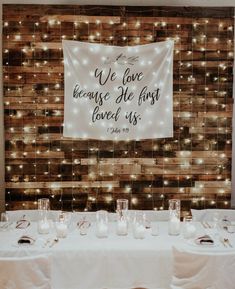 a white table topped with candles and a sign that says we love because he first loved us