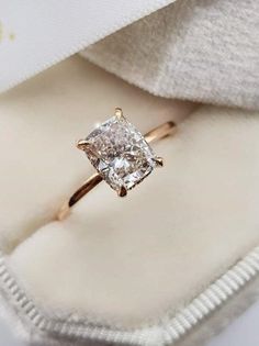 an engagement ring with a princess cut diamond in it on top of a white cloth