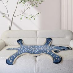 a white couch with a blue starfish pillow on it's back and a tree in the background