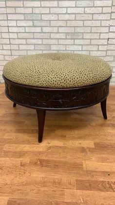 a leopard print foot stool sitting on top of a hard wood floor next to a brick wall