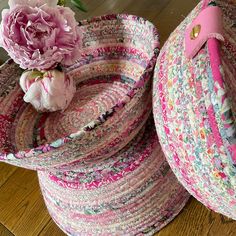 two baskets with pink flowers in them sitting on a wooden floor next to each other