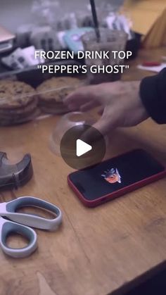 a person cutting up food on top of a wooden table with scissors and cell phone