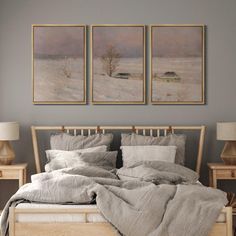 a bedroom with two paintings on the wall and a bed covered in grey linens