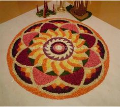 a colorful flower design is on the floor next to candles and other decorations in front of a candle holder