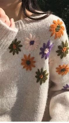 a close up of a person wearing a sweater with flowers on it