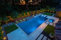 an outdoor swimming pool surrounded by grass and lights