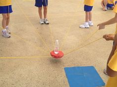 a group of young people standing around a red object with yellow string attached to it