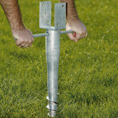 a man holding onto a metal pole in the middle of some grass with his hands on it