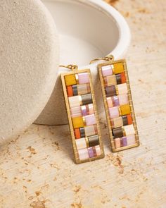 These elegantly constructed earrings feature Japanese Miyuki Tila beads that are meticulously woven inside a brass frame creating a mosaic-like structure. Reminiscent of stained glass, these earrings let a bit of light pass through. The gold-plated Tila beads add an extra touch of sparkle to them.  Their light weight and small size make them ideal for everyday use and they are versatile enough to take them from the office to an evening out.  These earrings are handmade by women artisans in Medellin, Colombia who receive fair working conditions and compensation for their skills. Materials: Miyuki Glass Tila Beads Brass Earring Component Gold-Plated Ear Wire Size: Length 1.8 Inches Width .5 Inch Tila Beads, Athens Ga, Brass Frame, Women Artisans, Brass Earrings, Jewelry Earrings Dangle, Stained Glass, Etsy Earrings, Lilac