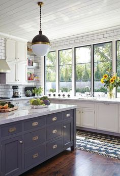 a large kitchen with white cabinets and wood flooring, along with an island in the middle