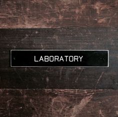 a sign that is on the side of a wooden door saying labratory,