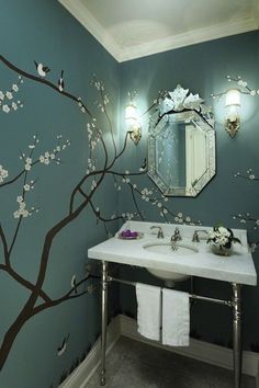 a bathroom with a tree painted on the wall and two sinks in front of it