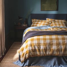 a bed with yellow and white checkered comforter next to a painting on the wall