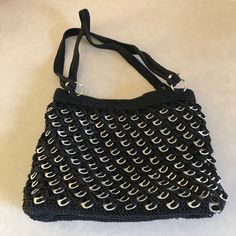 a crocheted black purse with silver handles on a white tablecloth covered surface