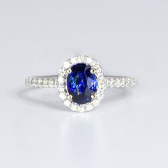 A stunning Classic Sapphire Halo Ring features a spectacular oval cut natural blue sapphire in royal blue colour that weights 0.94 carats. The sapphire is set in a classic diamond halo ring with accent diamonds on the band.  A lovely sapphire ring that is suitable for the everyday use and will enhance any look; a perfect piece to be chosen as an engagement ring.    SPECIFICATIONS: 1982540 Gemstone: Natural oval cut sapphire, 6.93 x 5.4 x 3.09mm approx. Weight: 0.94 carats. Side Stones: 34 x 1.1 round brilliant cut diamonds. Weight: 0.22 carats approx. Material: 18 carats white gold. Total Weight: 2.43 grams.  Ring Size: 6 or L.  We are a family owned business of gemologist, miners and dealers specialised in natural emeralds and colour gemstones with boutiques in the centre of the emerald w Blue Oval Gia Certified Halo Ring, Classic Blue Halo Ring, Oval Sapphire Halo Ring With Brilliant Cut, Classic Oval Sapphire Halo Ring, Oval Sapphire Halo Ring With Center Stone, Timeless Blue Ring With Halo Setting, Luxury Blue Oval Halo Ring, Timeless Blue Rings With Halo Setting, Blue Oval Diamond Halo Ring